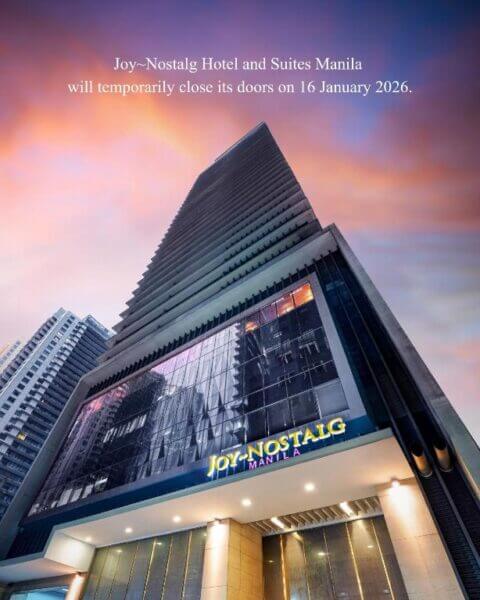 Tall building of Joy-Nostalg Hotel Manila with a sign announcing temporary closure starting 16 January 2026, set against a colorful sunset sky.