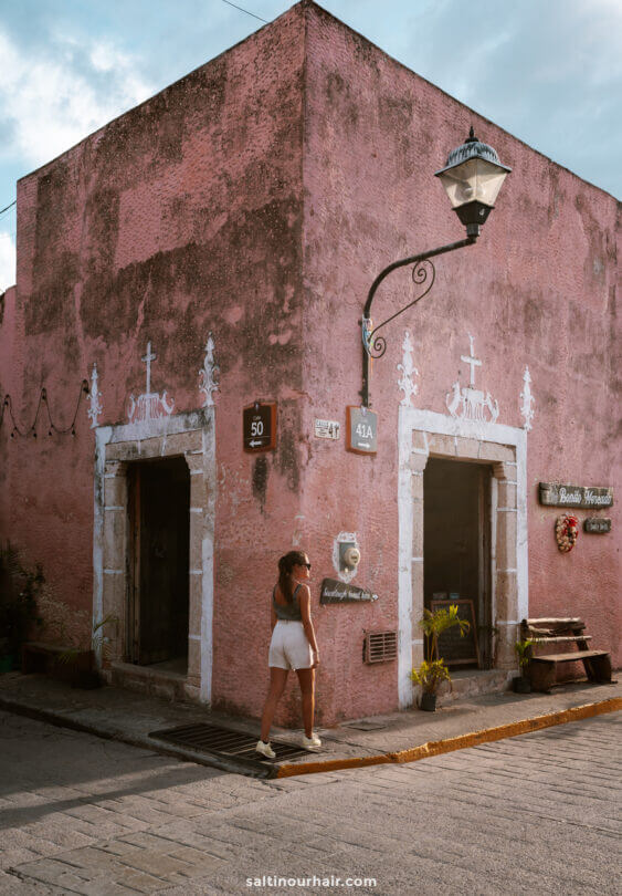 woman walking past an authenic pink shop in street valladolid mexico things to do in Yucatan Mexico