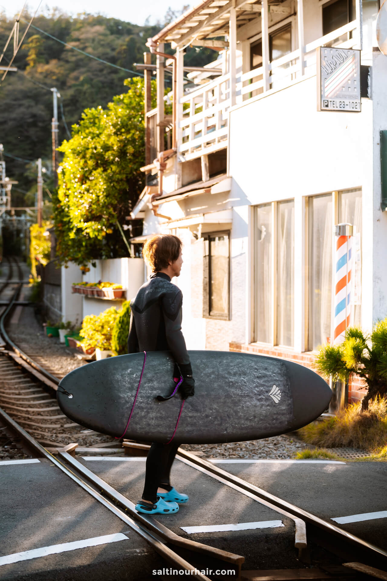 surfer crossing train line Kamakura Japan