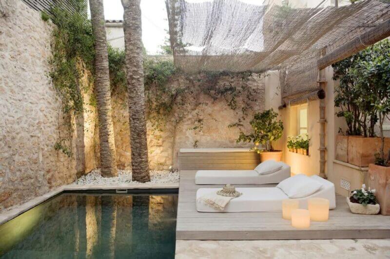 Small courtyard at S’Hotelet de Santanyi with a plunge pool, two lounge chairs, potted plants, stone walls, and a woven shade canopy—perfect for relaxing at this charming boutique hotel.