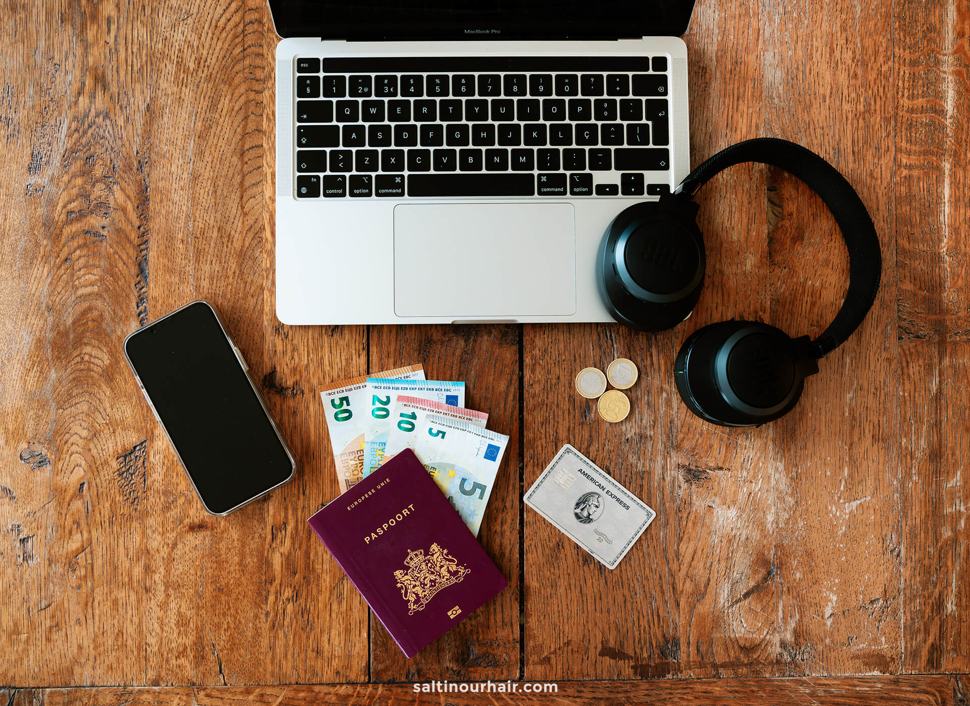 flat lay laptop passport money iphone headphones