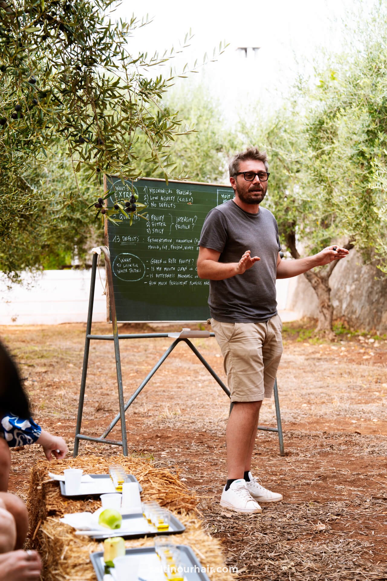 A man presents in front of a chalkboard, engaging attendees at an Olive Oil Tasting Ostuni event in puglia italy