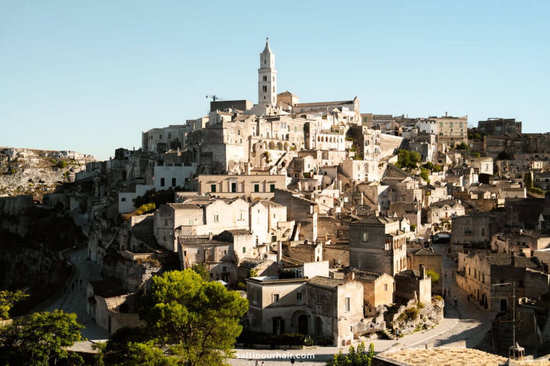 Hilltop view of Matera, Italy, showcasing clustered stone buildings and a prominent church tower