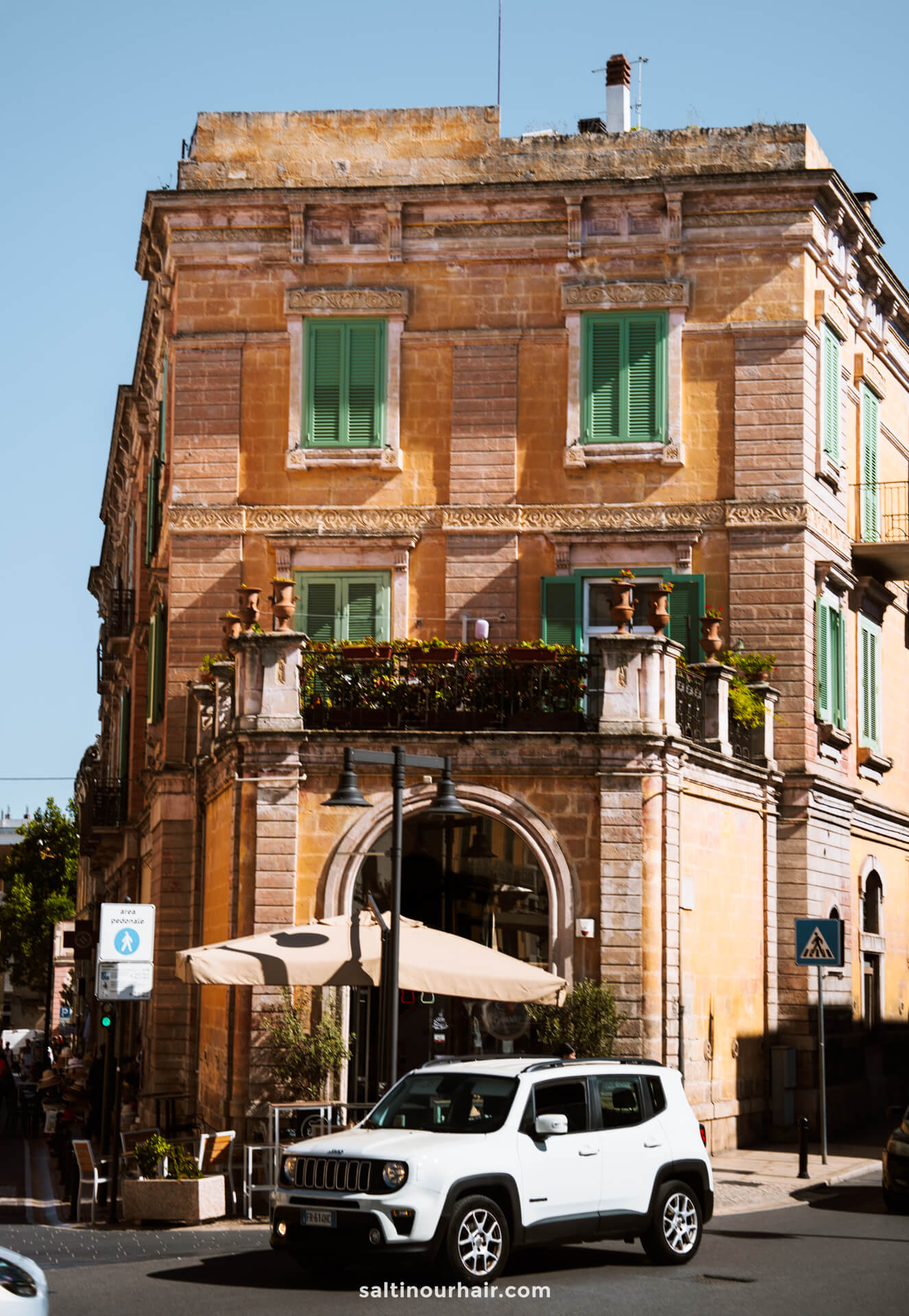 A car is parked in front of a historic, orange-brick building capturing the charm you'll discover when exploring how to get to Matera, Italy.