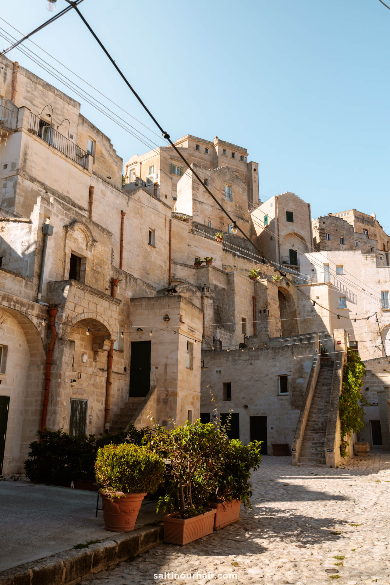 Old stone buildings, or Sassi di Matera, rise along a cobblestone street in Matera, Italy.