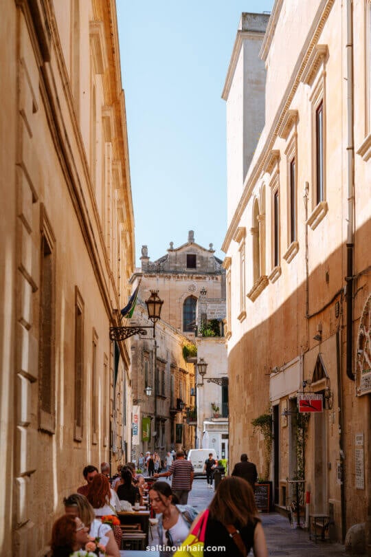 street in Lecce, Italy, with people walking and sitting at outdoor tables
