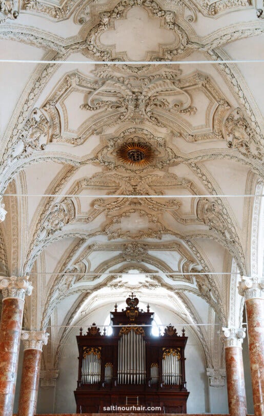 Baroque-style ceiling with intricate plasterwork and a large pipe organ below, supported by marble columnsâ€”a must-see highlight among the things to do in Innsbruck.