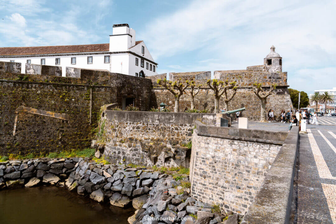 Fortaleza de S&atilde;o Br&aacute;s with white buildings and crenellated walls, bordered by a moat filled with rocks and water, a must-see among things to do in Ponta Delgada azores