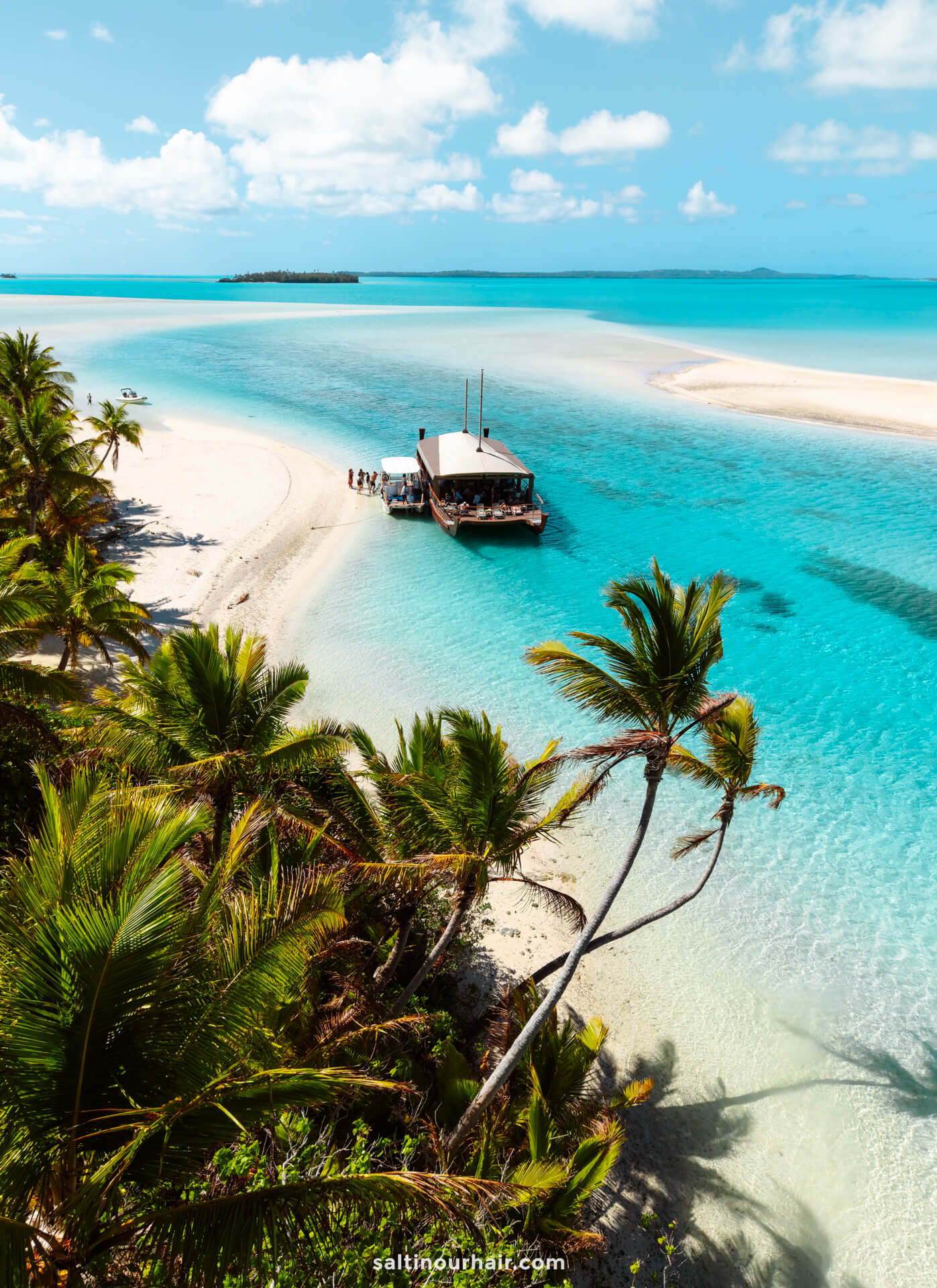 vaca cruise docked on one foot island with clear turquoise water, surrounded by palm trees under a sunny Aitutaki Island sky in cook islands