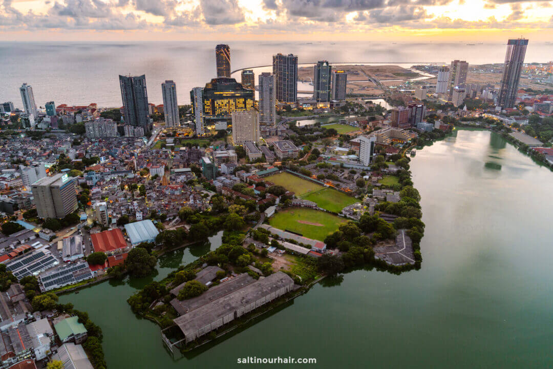 Aerial view of Colombo at sunset, featuring tall modern buildings, residential areas, green spaces, and the ocean viewed from the top of the Lotus Tower - one of the things to do in Colombo.