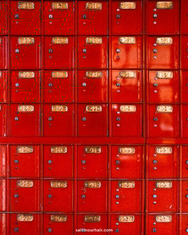 A wall of red metal mailboxes with gold number plates and keyholes, arranged in a grid pattern&mdash;reminiscent of the vintage charm found in Arrowtown.