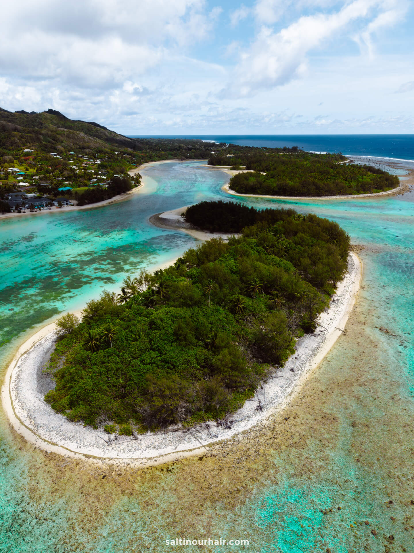 Aerial view of lush, small islands with white sandy beaches surrounded by turquoise water and a coastal village in the distance&mdash;perfect for exploring top things to do in Rarotonga, Cook Islands