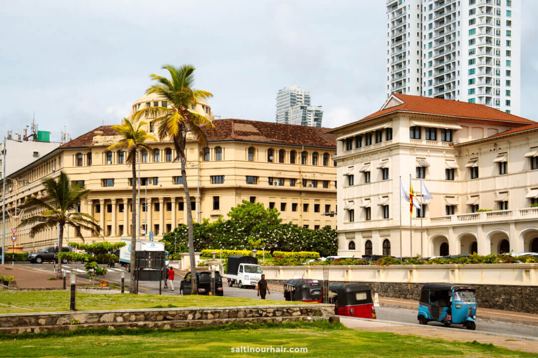Colonial-style buildings, palm trees, and tuk-tuks line a street in Colombo, Sri Lanka. 