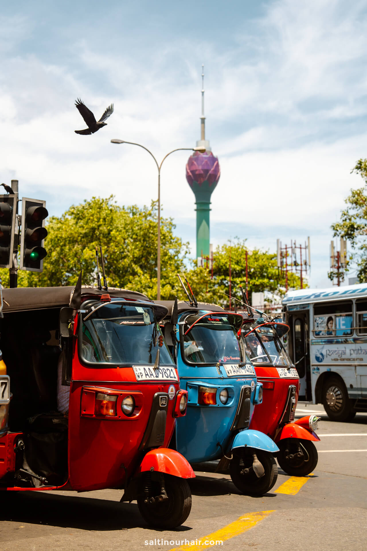 Three colorful tuk-tuks are parked beside a street, showing the perfect example of how to get around Colombo.