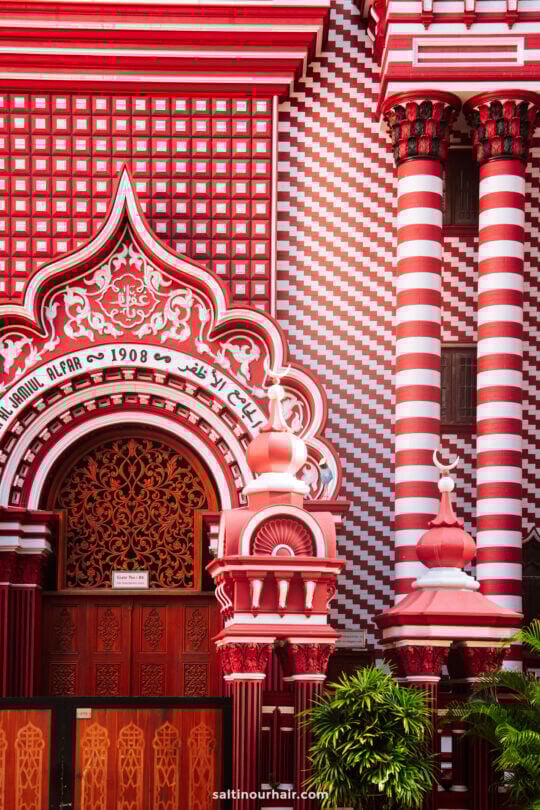 Facade of a mosque featuring red and white striped patterns, ornate arches, columns, Arabic script, and decorative architectural details&mdash;one of the iconic sights among the things to do in Colombo.
