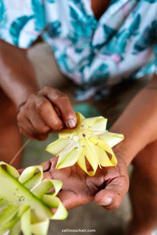 A person holds a woven yellow palm leaf star, demonstrating the intricate handmade craft with both hands&mdash;an artistry often discovered on a Bali cultural tour.