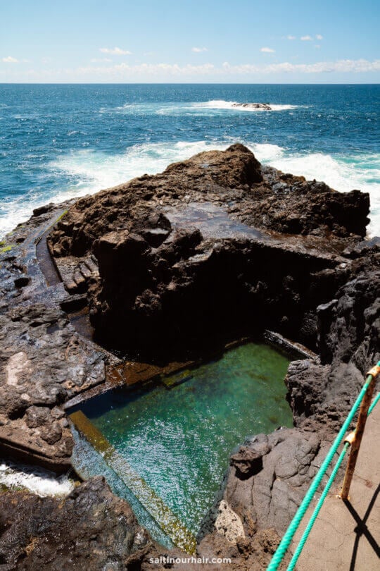 A natural ocean pool formed by rocks on the edge of the sea in La Palma, Canary Islands, with clear water and waves in the background under a blue sky—perfect for your next travel guide.